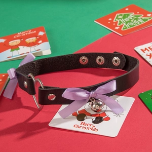 Gothic black leather choker with heart ring silver bell and purple bow on Christmas background