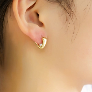 Gros plan de boucles d'oreilles dorées en U avec perles blanches sur un mannequin