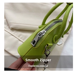 Close-up of high-quality green pebbled leather shell bag with smooth silver metal zipper