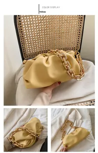 Macro detail of vibrant yellow dumpling bag with chunky gold chain strap and soft leather pleats