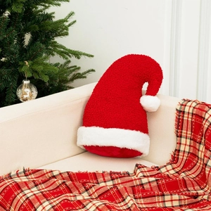 Coussin en peluche en forme de bonnet de Noël rouge et blanc sur un canapé beige