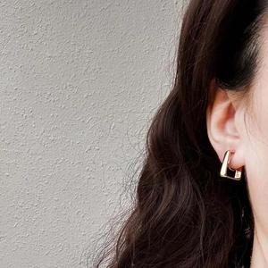Detail of square gold hoop earrings showing metallic luster and minimalist geometric design