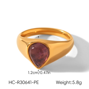 Nahaufnahme eines goldenen Edelstahlrings mit birnenförmigem lila Stein