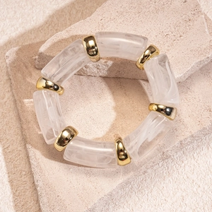 Close-up of geometric acrylic bead bracelet with polished gold spacers on stone surface