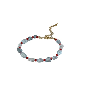 Bracciale in acquamarina e agata rossa con chiusura dorata su sfondo bianco