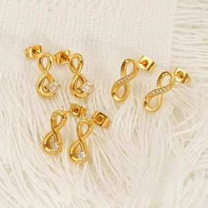 Trois paires de boucles d'oreilles infini en or avec zircons cubiques sur tissu blanc