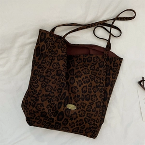 Macro detail of leopard print tote bag featuring a gold metallic logo and inner lining