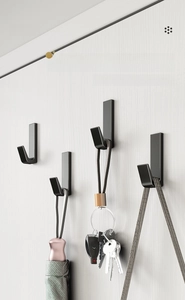 Detail of matte black J-shaped hooks holding a folding umbrella and keys on wall