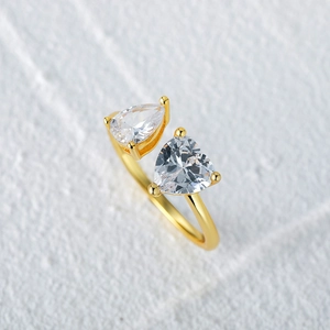 Detail of gold open ring featuring sparkling pear and heart shaped clear gemstones