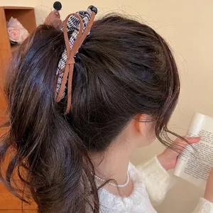 Plaid fabric dachshund hair clip with brown leather bow shown in use on a ponytail