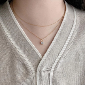 Close-up of double-layer gold chain necklace with square zircon lock pendant on model