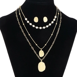 Gold multi-layer pearl necklace and earring set displayed on a professional black model bust
