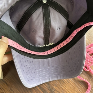 Macro detail of measuring the inner circumference of the purple cotton baseball cap