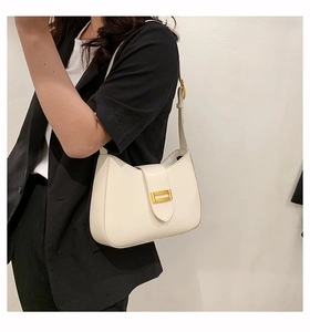 Detail of cream baguette shoulder bag featuring a vintage gold rectangular metal buckle