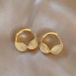 Detailed view of golden twisted hoop earrings on an elegant champagne silk background