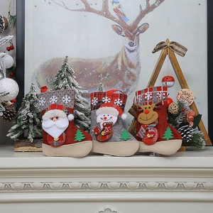 Trois chaussettes de Noël avec Père Noël, bonhomme de neige et renne sur une cheminée