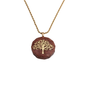 Close-up of golden tree of life pendant featuring dark red resin stone on twist chain
