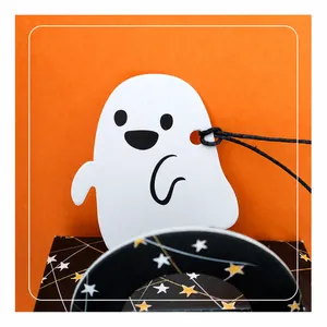 Close-up of a cute cartoon ghost gift tag with black string on a vibrant orange background