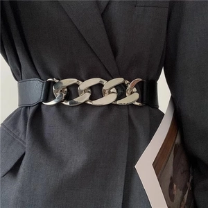 Fashion punk waist belt with bold silver metal chain buckle over a charcoal grey suit blazer