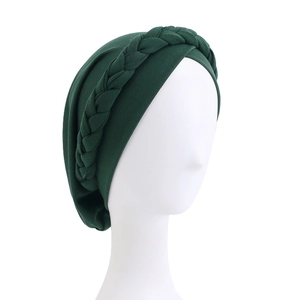 Detail of dark green turban cap showing elastic fabric and thick braided headband decoration