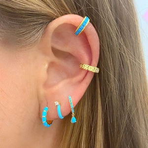 Detail showing stacked turquoise enamel and gold-plated earrings with zircon accents