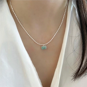 Detail of 925 sterling silver chain with a rectangular green stone pendant on neck