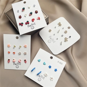 Close-up of fruit and bear stud earrings set with S925 silver needles on satin