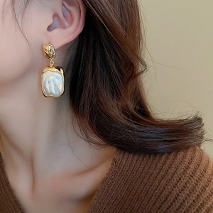 Vintage gold pleated metal square earrings with faux pearl worn on a model