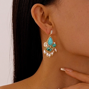 Close-up of vintage gold flower drop earring with turquoise stone and pearl tassels