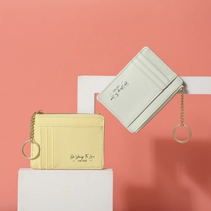 Close-up of pastel yellow and green textured leather wallets with gold zipper and keychains