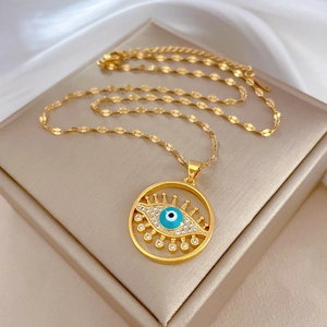 Macro shot of gold Evil Eye pendant with blue stone and crystals on beige box