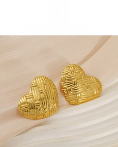 Macro detail of 18K gold plated heart earrings with elegant woven texture on silk