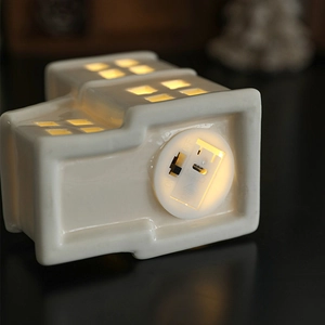 White ceramic Christmas house ornament with LED light and battery switch on bottom