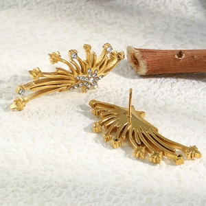 Vue macro de boucles d'oreilles ailes dorées avec zircons et cristaux blancs