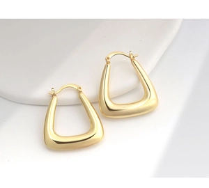 Macro shot of polished gold hollow U-shaped hoop earrings with secure clasp detail