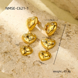 Détail de boucles d'oreilles cœur en or 18K avec gravures d'étoiles et strass brillants