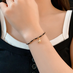 Detail of bohemian black bead bracelet with a golden shell pendant on a woman's wrist