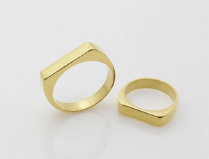 Macro shot of two polished gold-plated stainless steel rings with flat rectangular tops