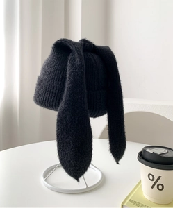 Detail of black knit hat with long rabbit ears and soft texture on a display stand