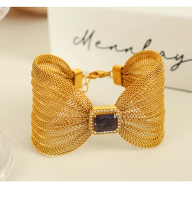Macro shot of gold mesh bow bracelet featuring a square purple stone with white crystal halo