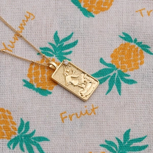 Détail macro du collier pendentif soleil doré avec relief tarot sur un tissu
