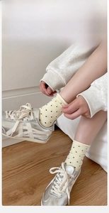 Close-up of light yellow polka dot socks with ribbed elastic cuffs and breathable cotton fabric