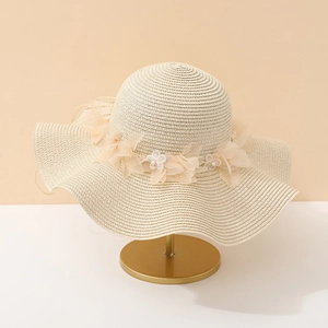 Détail d'un chapeau de paille beige avec fleurs en tulle et perles sur support en métal