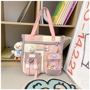 Detail of multi-pocket canvas school bag with cute pins and plush pendant decoration