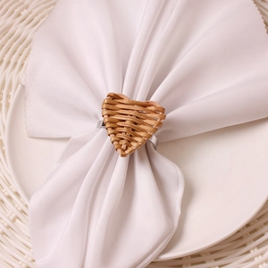 Handmade woven heart napkin ring in natural brown rattan on a white napkin