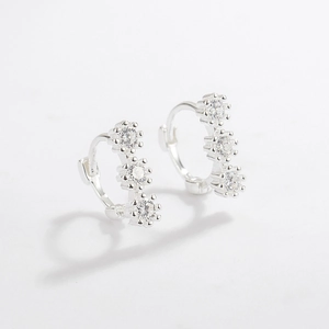 Detail of 925 sterling silver hoop earrings with three prong-set cubic zirconia stones