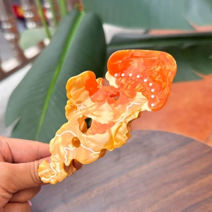 Close-up of amber patterned acetate hair claw clip with orange translucent texture