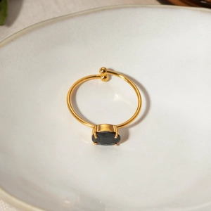 Macro detail of 18k gold plated ring with black oval zircon on white ceramic tray