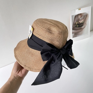 Dettaglio del cappello da sole in lino con fiocco nero ed etichetta protettiva UV