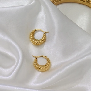Detailed view of gold plated croissant hoop earrings on elegant white satin fabric